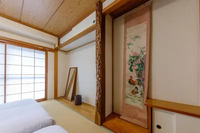 a bedroom with a bed and a painting on the wall at \u306a\u306a\u5bbf \u6d45\u8349\u4e09\u30ce\u8f2a in Tokyo