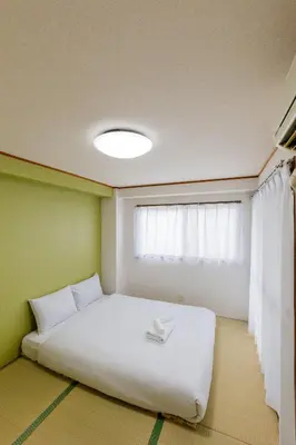 a bedroom with a white bed and a window at \u306a\u306a\u5bbf \u6d45\u8349\u4e09\u30ce\u8f2a in Tokyo