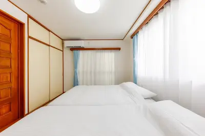 a small bedroom with two beds and a window at \u306a\u306a\u5bbf \u6d45\u8349\u4e09\u30ce\u8f2a in Tokyo
