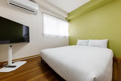 a bedroom with a white bed and a flat screen tv at \u306a\u306a\u5bbf \u6d45\u8349\u4e09\u30ce\u8f2a in Tokyo