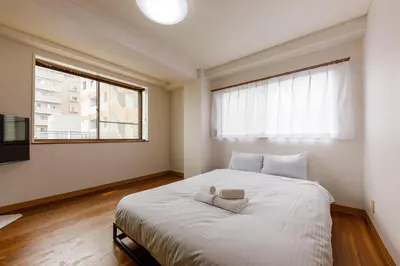 a bedroom with a large white bed with a window at \u306a\u306a\u5bbf \u6d45\u8349\u4e09\u30ce\u8f2a in Tokyo