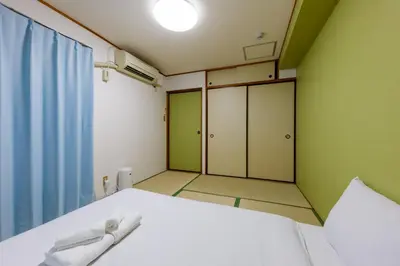a small room with a bed and a window at \u306a\u306a\u5bbf \u6d45\u8349\u4e09\u30ce\u8f2a in Tokyo
