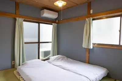 a bed in a room with two windows at \u5927\u798f\u30cf\u30a6\u30b92 in Tokyo