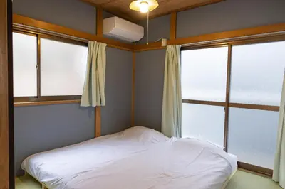 a small bedroom with a bed and two windows at \u5927\u798f\u30cf\u30a6\u30b92 in Tokyo