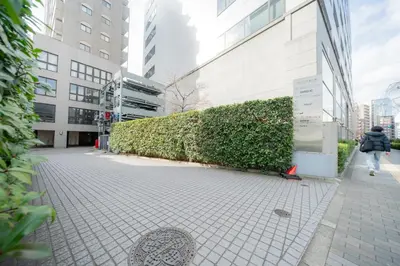 a person walking down a sidewalk in front of a building at unito residence EBISU STATION North in Tokyo