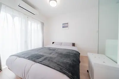 a white bedroom with a bed and a window at unito residence EBISU STATION North in Tokyo