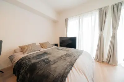 a bedroom with a large bed and a large window at unito residence EBISU STATION North in Tokyo