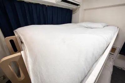 an empty bed in a room with a blue curtain at GrAce Room IKEBUKURO in Tokyo