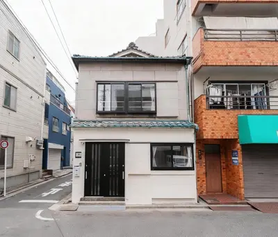 an apartment building with a door on a street at NISHIKI Ryokan\u9326\u65c5\u9928 in Tokyo