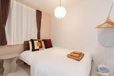 a bedroom with a white bed and a pendant light at \u30a2\u30f3\u30c9\u30b9\u30c6\u30a4\u5343\u4f4f\u4ef2\u753aa in Tokyo