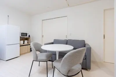 a living room with a table and chairs and a couch at \u30a2\u30f3\u30c9\u30b9\u30c6\u30a4\u5343\u4f4f\u4ef2\u753ab in Tokyo