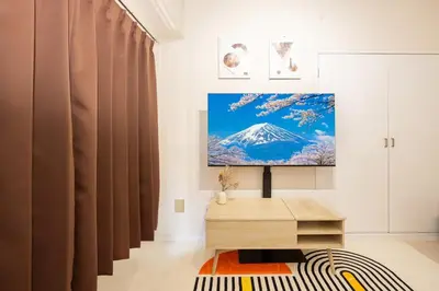 a living room with a television on a wall at 8 mins walk to Ikebukuro, 6 mins to Kanamecho Station, Max 2 people, Direct access to Tokyo, Shinjuku, Shibuya, Ueno 503 in Tokyo