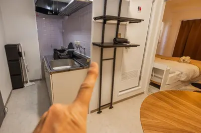 a person is reaching for a counter in a small kitchen at 8 minutes on foot from Ikebukuro, 6 minutes on foot from Kanamecho Station, Maximum 2 people, Direct to Tokyo, Shinjuku, Shibuya, Ueno 102 in Tokyo