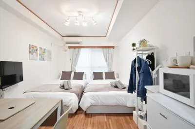 two beds in a white room with a tv at Setagaya Quiet Residential Apartment203 in Tokyo