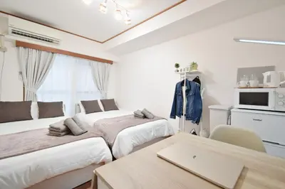 a bedroom with two beds and a table with a laptop at Setagaya Quiet Residential Apartment203 in Tokyo
