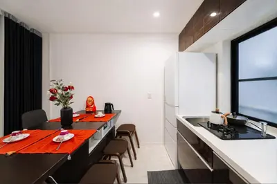 a kitchen with a long table with chairs and a refrigerator at Alice \u65e5\u66ae\u91cc \u5c71\u624b\u7ebf\u6b65\u884c6\u5206\u949f \u6210\u7530\u76f4\u8fbe \u4e0a\u91ceAsakusa\u76f4\u8fbe \u6574\u5957\u5bb6\u5ead\u623f in Tokyo