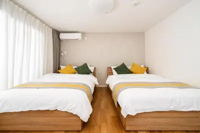 two beds in a room with white and yellow pillows at Alice \u65e5\u66ae\u91cc \u5c71\u624b\u7ebf\u6b65\u884c6\u5206\u949f \u6210\u7530\u76f4\u8fbe \u4e0a\u91ceAsakusa\u76f4\u8fbe \u6574\u5957\u5bb6\u5ead\u623f in Tokyo