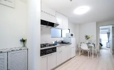 a kitchen with white cabinets and a table with chairs at Kasai disney access hotel in Tokyo