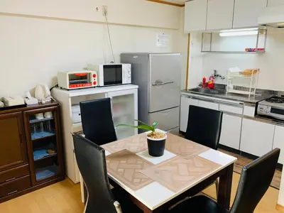 a kitchen with a table and chairs and a kitchen with a refrigerator at HOTEL k &m in Tokyo