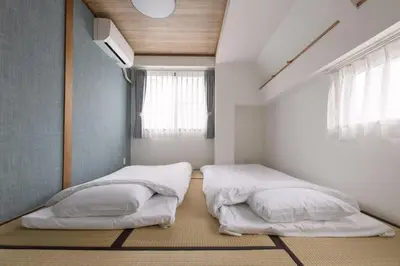 two beds in a small room with a window at Shinjuku 6-chome City Stay 4F \u65b0\u5bbf6\u4e01\u76ee \u30b7\u30c6\u30a3\u30b9\u30c6\u30a4 4F in Tokyo
