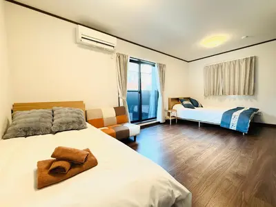 a bedroom with a bed and a couch and a window at Nexus Villa Morishita in Tokyo