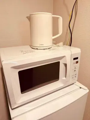 a white microwave with a bucket on top of it at Nexus Villa Morishita in Tokyo