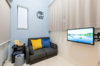 a living room with a couch and a tv on a wall at Tsumugi Yado \u5927\u4e45\u4fdd \u30de\u30f3\u30b9\u30ea\u30fc \u30ed\u30f3\u30b0\u30b9\u30c6\u30a4 in Tokyo