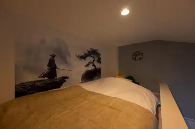 a bedroom with a large bed with a painting on the wall at Tsumugi Yado \u5927\u4e45\u4fdd \u30de\u30f3\u30b9\u30ea\u30fc \u30ed\u30f3\u30b0\u30b9\u30c6\u30a4 in Tokyo