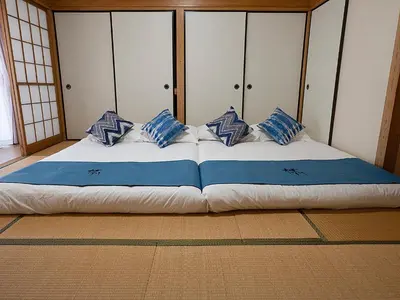 a large bed with blue and white pillows on it at \u685c\u306e\u5ddd79 \u5317\u5343\u4f4f\u5bb6\u5ead\u516c\u5bd36-8\u4eba\u4e28Kita Senju family apartments for 6-8 people in Tokyo