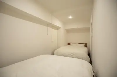 a white bedroom with two beds in it at NIYS apartments 74type in Tokyo
