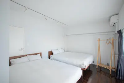 two beds in a room with white walls and wood floors at NIYS apartments 74type in Tokyo