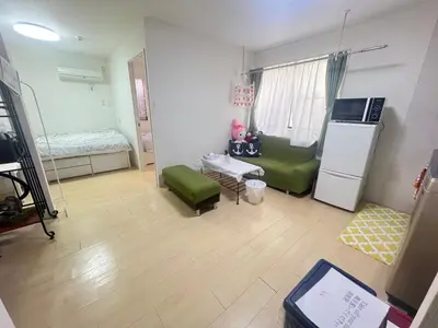 a living room with a refrigerator and a green couch at happy home 102\u5ba4\u65b0\u5927\u4e45\u4fdd\u65b0\u5bbf\u30a8\u30ea\u30a2 in Tokyo