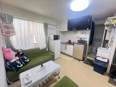a small living room with a green couch and a kitchen at happy home 102\u5ba4\u65b0\u5927\u4e45\u4fdd\u65b0\u5bbf\u30a8\u30ea\u30a2 in Tokyo