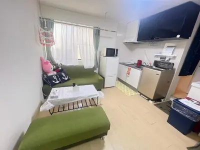 a living room with a green couch and a kitchen at happy home 102\u5ba4\u65b0\u5927\u4e45\u4fdd\u65b0\u5bbf\u30a8\u30ea\u30a2 in Tokyo