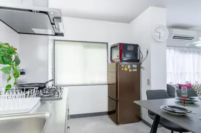 a small kitchen with a table and a refrigerator at HanaStay-Tokyo Ueno 2 Stops in Tokyo