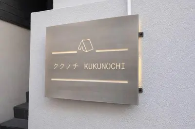 a metal sign on a wall with a kuomonuth at Kukunochi in Tokyo
