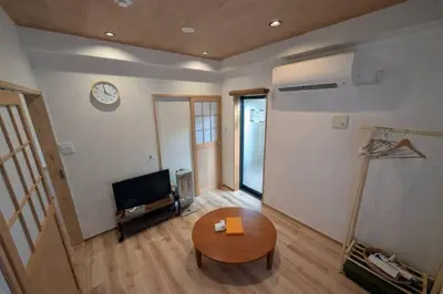 a living room with a table and a clock on the wall at Kukunochi in Tokyo
