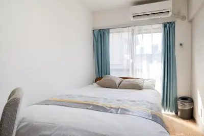a bedroom with a bed and a window with blue curtains at Shinjuku,Higashi Shinjuku Sta, 5min walk,WiFi in Tokyo