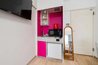 a small kitchen with pink walls and a mirror at Shinjuku,Higashi Shinjuku Sta, 5min walk,WiFi in Tokyo