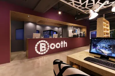 a person sitting at a desk with a computer in front of a booth at Booth Netcafe & Capsule in Tokyo
