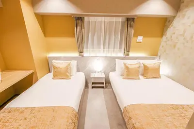 a small room with two beds and a window at Premium Apartment Hotel Tokyo Shinjuku in Tokyo
