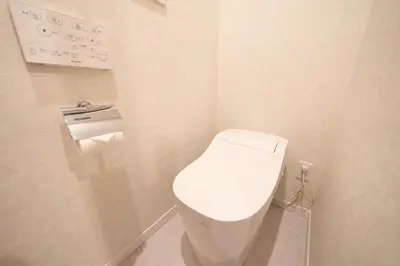 a white toilet in a bathroom with a toilet paper dispenser at HOTEL Edogawa in Tokyo