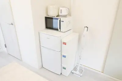 a microwave sitting on top of a refrigerator at \u56db\u3064\u6728\u6238\u5efa2165 in Tokyo