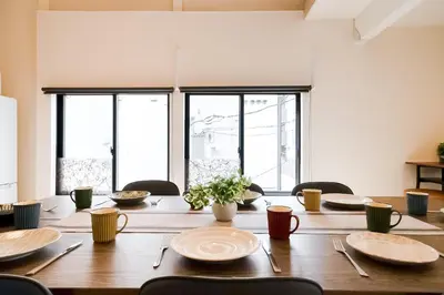 a large wooden table with chairs and plates on it at Yuka's House Otsuka Perfect for children in Tokyo