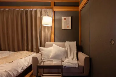 a bedroom with a bed and a chair and a lamp at Y's Hotel in Tokyo
