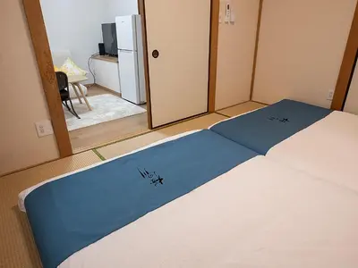 a bedroom with a bed with a blue and white blanket at \u685c\u306e\u5ddd78 \u5317\u5343\u4f4f\u4e00\u6237\u5efa6-8\u4eba\u4e28Kita Senju villa for 6-8 people in Tokyo