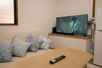 a living room with a couch with a television and a remote control at \u685c\u306e\u5ddd78 \u5317\u5343\u4f4f\u4e00\u6237\u5efa6-8\u4eba\u4e28Kita Senju villa for 6-8 people in Tokyo