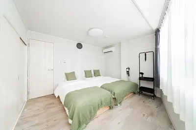 a white bedroom with two beds and a window at Alice \u6696\u5c4b \u845b\u9970\u533a\u6e29\u99a8\u516c\u5bd3 \u6b65\u884c2\u5206\u949f\u5230\u8f66\u7ad9 \u673a\u573a\u4ea4\u901a\u4fbf\u5229 \u6700\u591a4\u4eba in Tokyo