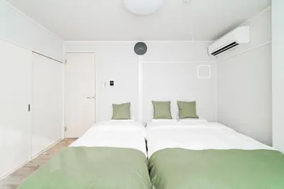 two beds in a white room with green sheets at Alice \u6696\u5c4b \u845b\u9970\u533a\u6e29\u99a8\u516c\u5bd3 \u6b65\u884c2\u5206\u949f\u5230\u8f66\u7ad9 \u673a\u573a\u4ea4\u901a\u4fbf\u5229 \u6700\u591a4\u4eba in Tokyo