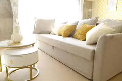 a living room with a white couch with yellow pillows at \u6771\u967d\u753a\u99c5\u5f92\u6b695\u5206 \u6700\u59275\u540d \u30d5\u30a1\u30df\u30ea\u30fc\u5411\u3051 \u6771\u4eac\u99c510\u5206 \u30c7\u30a3\u30ba\u30cb\u30fc \u30b9\u30ab\u30a4\u30c4\u30ea\u30fc\u4fbf\u5229 in Tokyo